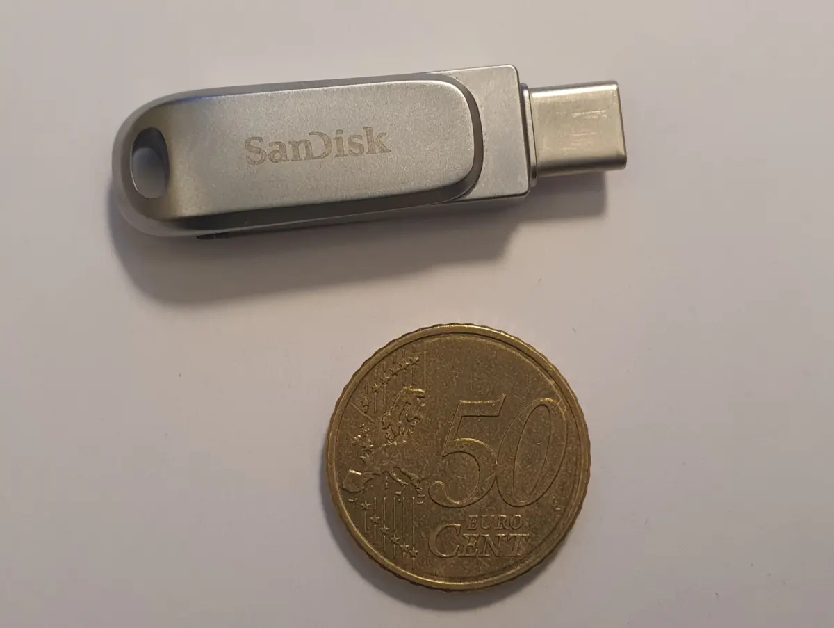 A compact USB flash drive next to a coin for scale